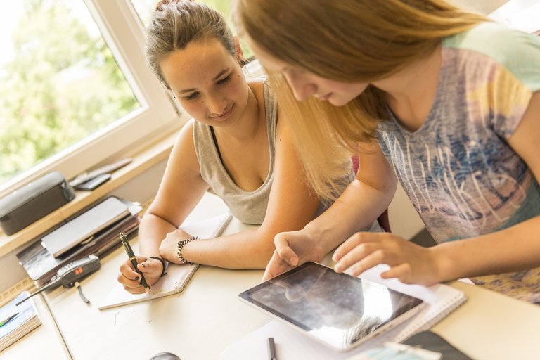 Duas garotas na hora de trabalho com a ajuda de um comprimido