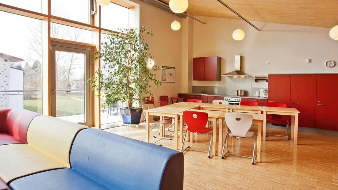 Área comum superior no Wiesenhaus com varanda: com cozinha vermelha, grupo de mesa de jantar e área de estar em primeiro plano