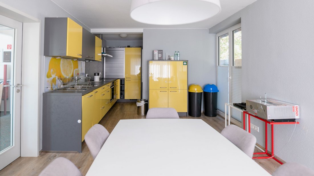 Cozinha moderna em cinza-amarelo com grupo de mesa de jantar em primeiro plano
